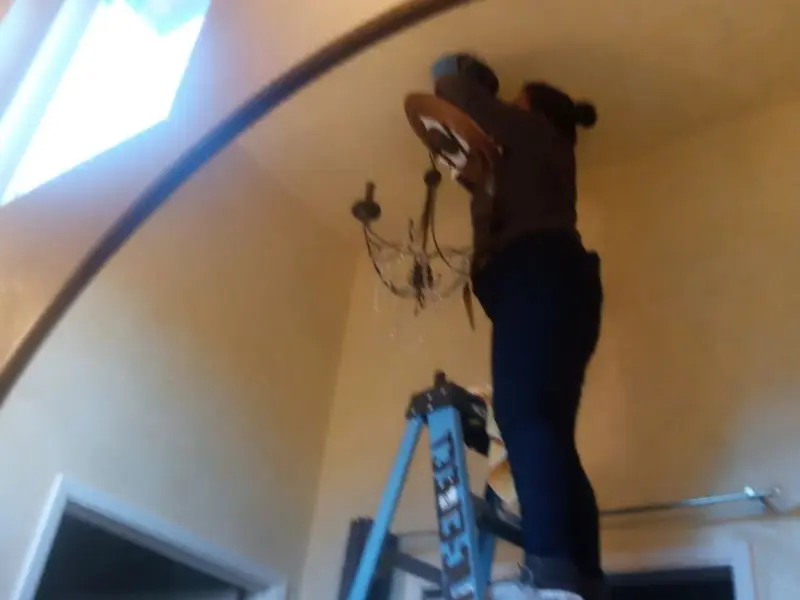 Electrician installing a chandelier in a Fair Lakes residence